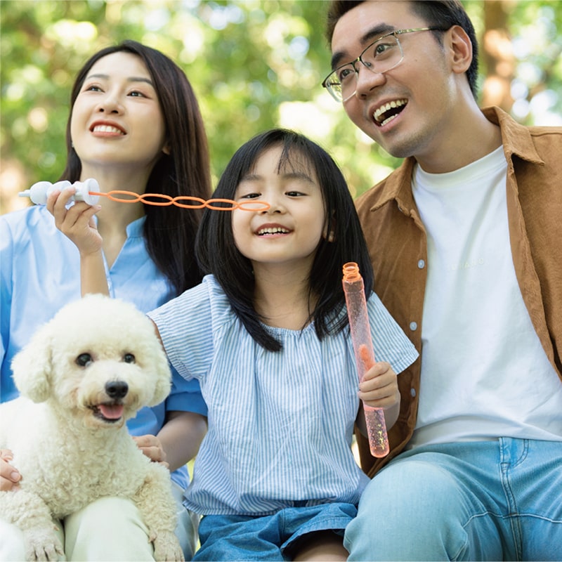 自然の中でシャボン玉をする親子と愛犬